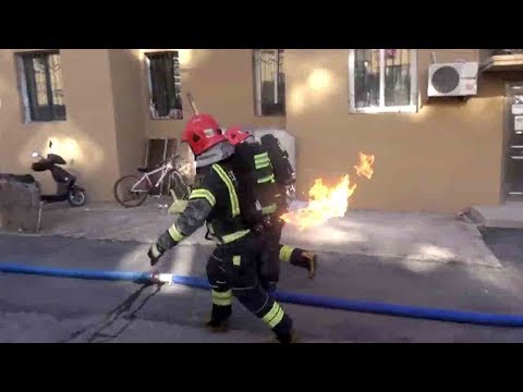 firefighter in china races out of housing block with burning gas tank in hands